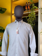 White striped shirt on a mannequin with a yellow wall and plants in the background